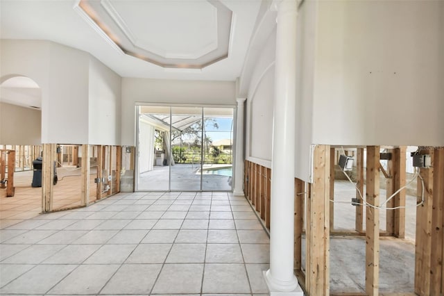 corridor with ornamental molding, a raised ceiling, and light tile patterned floors