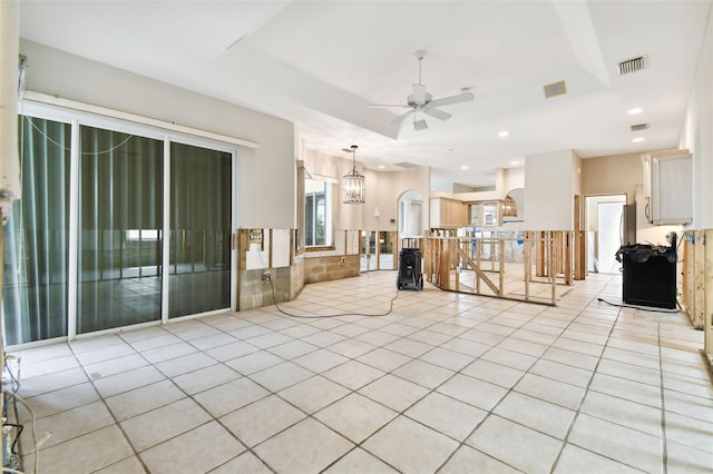 unfurnished living room with light tile patterned flooring and ceiling fan with notable chandelier