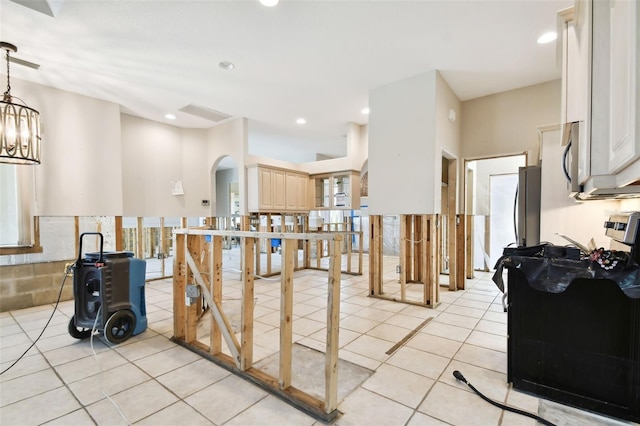 kitchen featuring light tile patterned flooring, hanging light fixtures, light brown cabinets, and black range