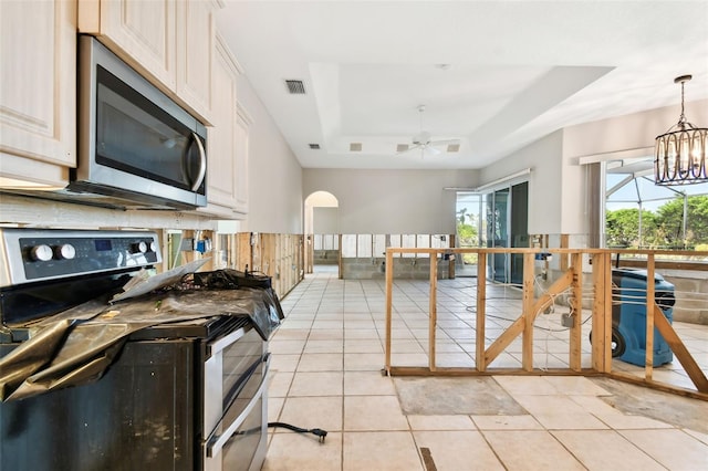 kitchen featuring pendant lighting, a raised ceiling, light tile patterned floors, electric range, and ceiling fan with notable chandelier