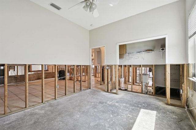 interior space featuring a towering ceiling, concrete floors, and ceiling fan