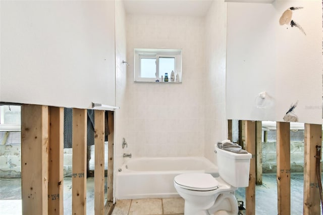 bathroom with tile patterned floors, tiled shower / bath combo, toilet, and a wealth of natural light