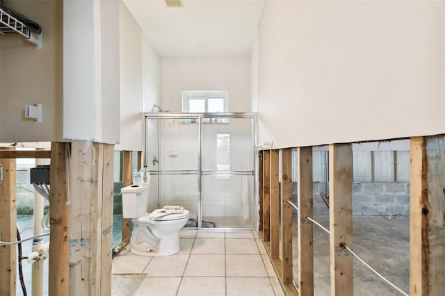 bathroom with tile patterned floors, toilet, and a shower with shower door