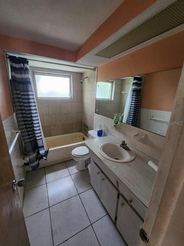 full bathroom with shower / tub combo, toilet, tile patterned floors, tile walls, and vanity