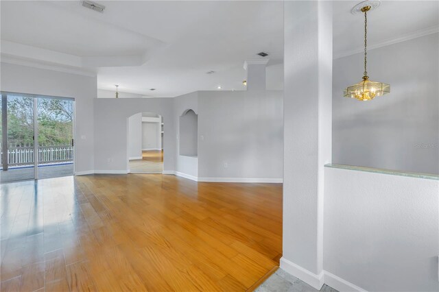 empty room with a chandelier, hardwood / wood-style flooring, and crown molding