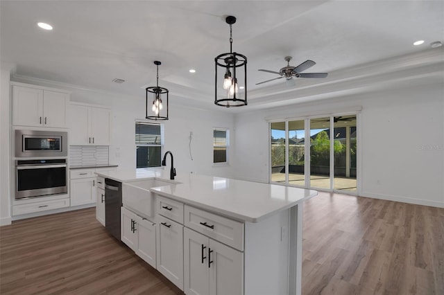 kitchen with sink, a center island with sink, white cabinetry, appliances with stainless steel finishes, and light wood-type flooring