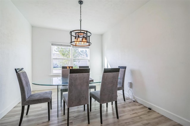 dining room with light wood-type flooring and a notable chandelier