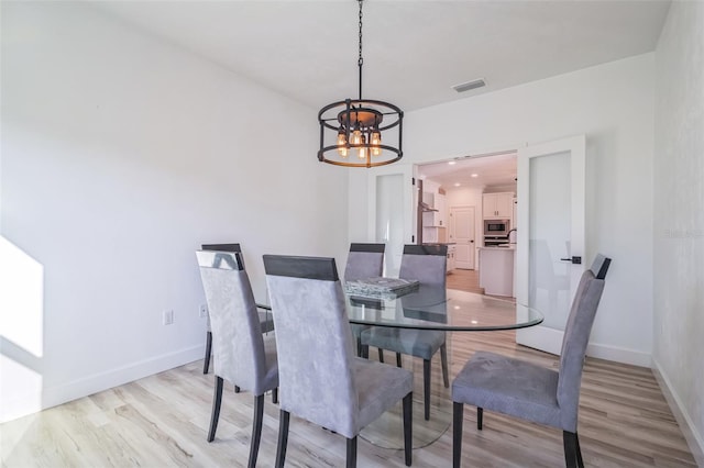 dining area featuring light wood-type flooring and an inviting chandelier