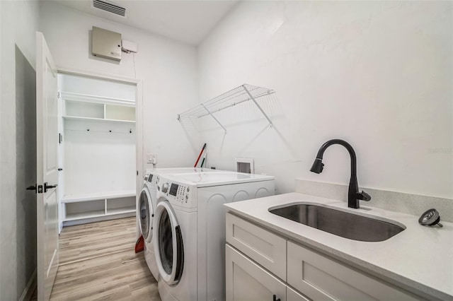 washroom with light wood-type flooring, separate washer and dryer, sink, and cabinets