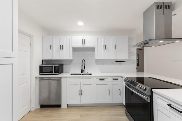 kitchen featuring sink, appliances with stainless steel finishes, wall chimney range hood, and white cabinetry