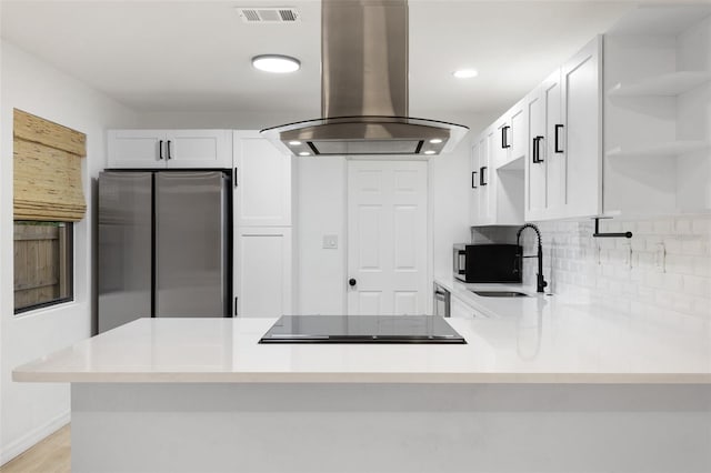 kitchen with kitchen peninsula, sink, stainless steel fridge, and island range hood