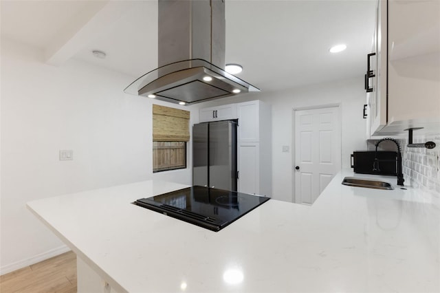 kitchen with white cabinetry, island exhaust hood, sink, kitchen peninsula, and black electric cooktop