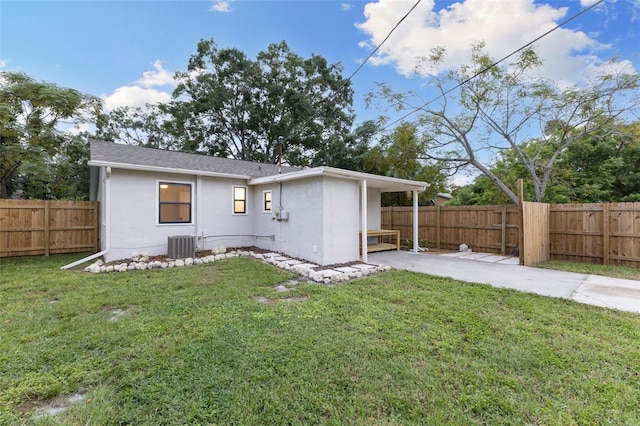 rear view of property featuring central air condition unit and a lawn