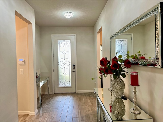 doorway with light wood-type flooring and a textured ceiling