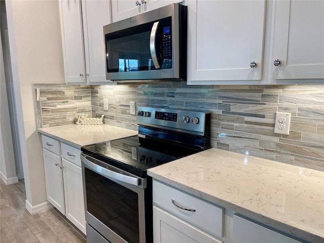 kitchen featuring light stone counters, stainless steel appliances, tasteful backsplash, white cabinetry, and light hardwood / wood-style flooring