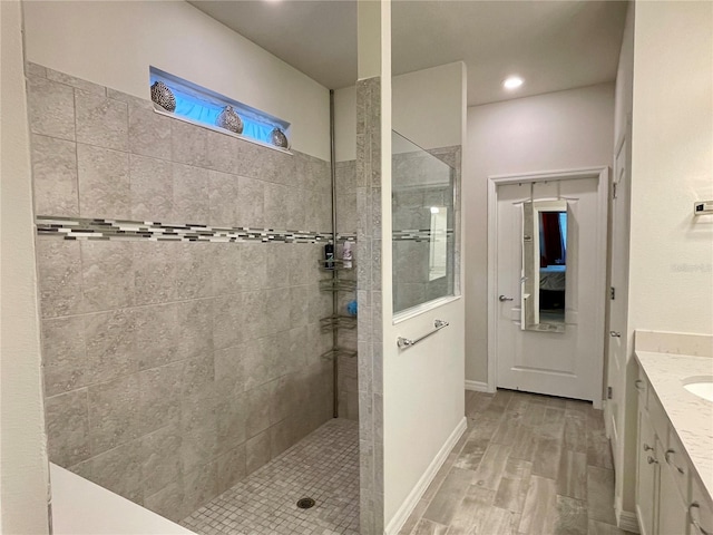 bathroom featuring vanity, a tile shower, and hardwood / wood-style flooring