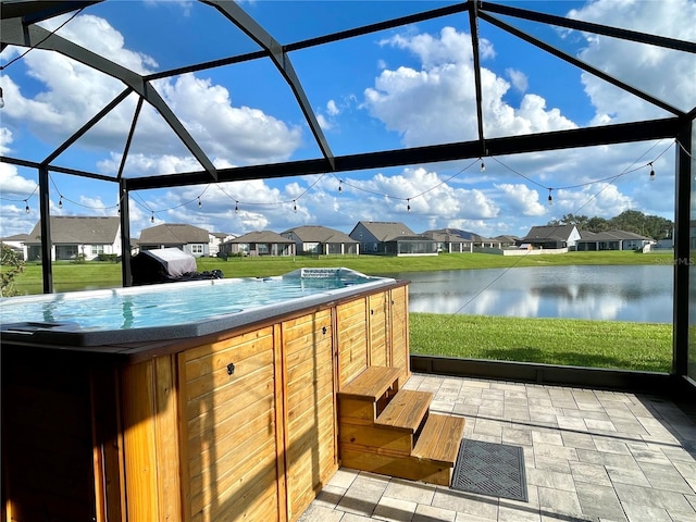 view of patio with a lanai and a water view