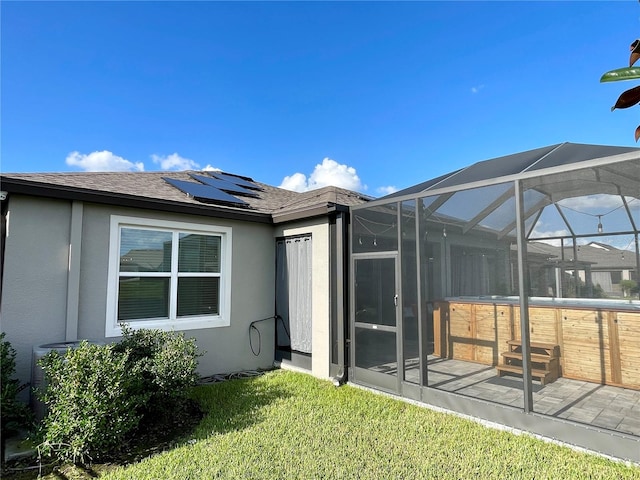 rear view of house featuring glass enclosure, a patio, and a lawn