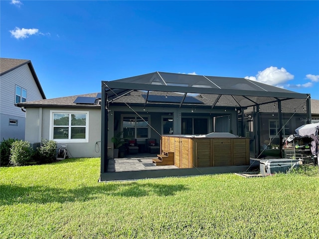 back of property with a patio area, a yard, a lanai, and a hot tub