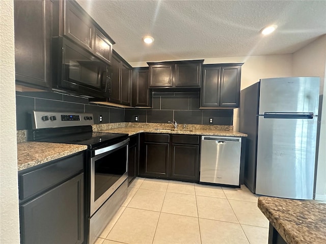 kitchen with appliances with stainless steel finishes, tasteful backsplash, light stone counters, and sink