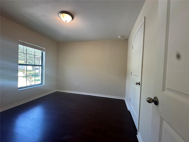 unfurnished room featuring dark hardwood / wood-style flooring and a textured ceiling