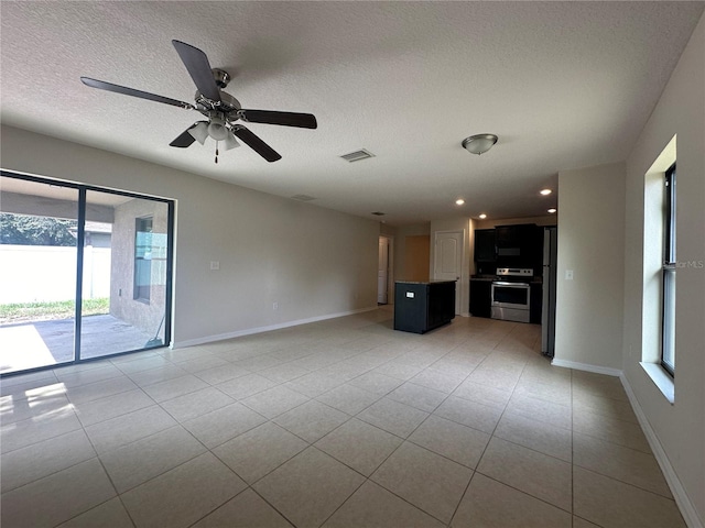 unfurnished living room featuring ceiling fan, light tile patterned flooring, and a textured ceiling