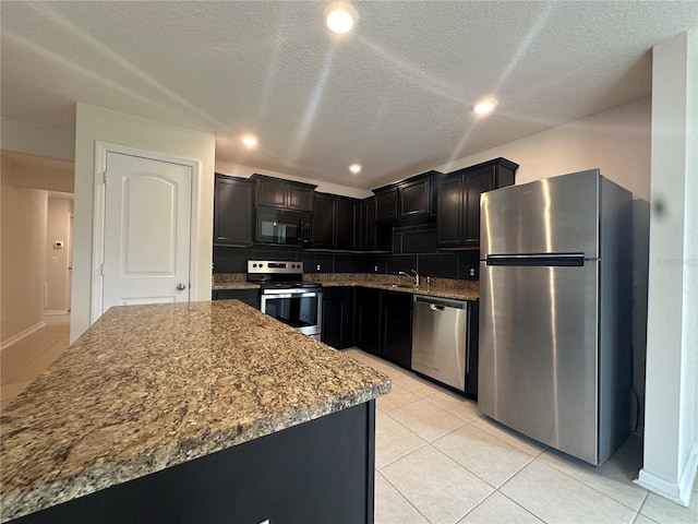 kitchen featuring light tile patterned flooring, a textured ceiling, appliances with stainless steel finishes, and tasteful backsplash