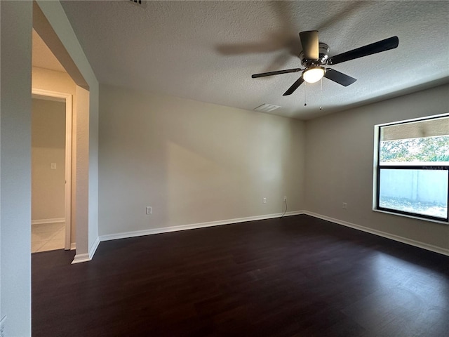 spare room with a textured ceiling, ceiling fan, and dark wood-type flooring