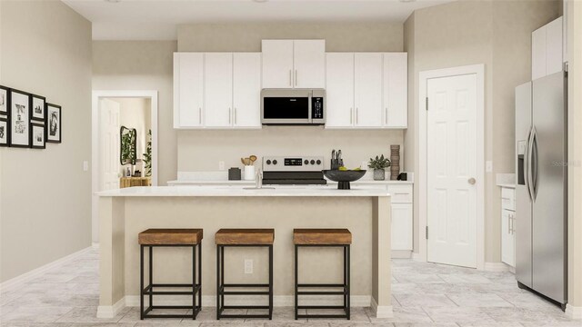 kitchen featuring white cabinets, an island with sink, stainless steel appliances, and a kitchen bar