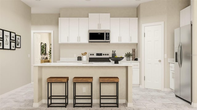 kitchen featuring a center island with sink, a breakfast bar area, appliances with stainless steel finishes, and white cabinets