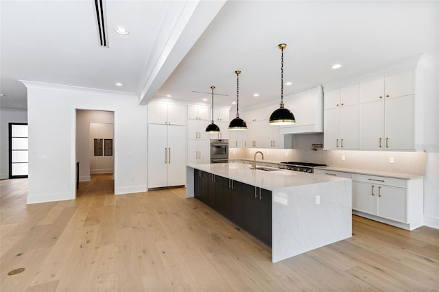 kitchen with light wood-type flooring, hanging light fixtures, white cabinetry, a large island, and ornamental molding