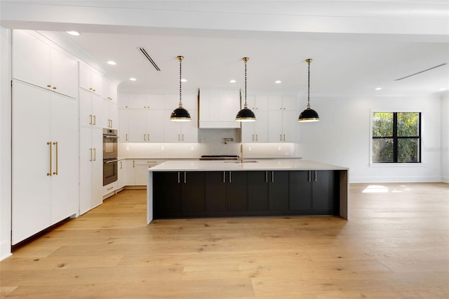 kitchen featuring white cabinets, a large island, and light wood-type flooring