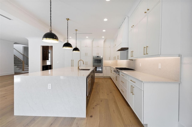 kitchen with sink, white cabinetry, appliances with stainless steel finishes, a spacious island, and light hardwood / wood-style floors