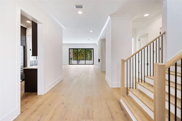 hall with ornamental molding and light hardwood / wood-style flooring