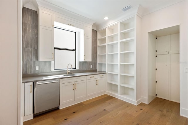 kitchen with light wood-type flooring, sink, white cabinetry, and stainless steel dishwasher