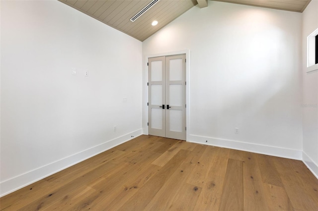 empty room featuring french doors, vaulted ceiling with beams, hardwood / wood-style floors, and wooden ceiling