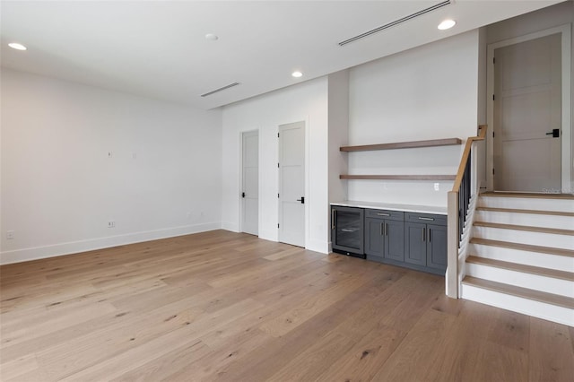 unfurnished living room with beverage cooler and light hardwood / wood-style floors