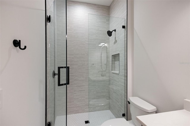 bathroom featuring a shower with door, vanity, and toilet