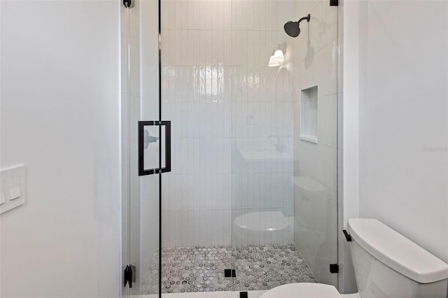 bathroom featuring toilet and a shower with door