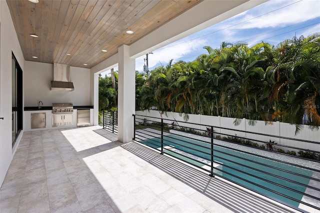 view of patio / terrace featuring grilling area, a fenced in pool, sink, and exterior kitchen