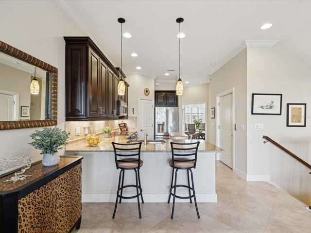 kitchen featuring a kitchen bar, kitchen peninsula, hanging light fixtures, stainless steel appliances, and light stone counters