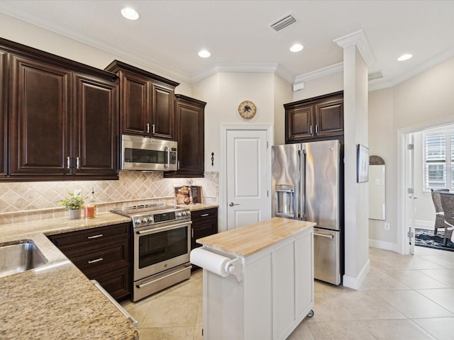 kitchen featuring appliances with stainless steel finishes, butcher block counters, dark brown cabinetry, ornamental molding, and light tile patterned floors