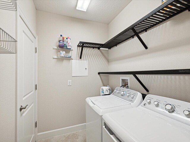 washroom with washer and dryer, a textured ceiling, and light tile patterned floors