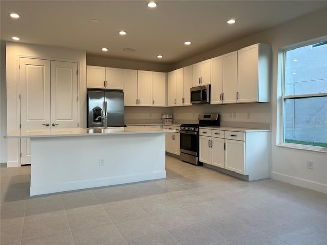 kitchen featuring an island with sink, white cabinets, stainless steel appliances, and light tile patterned floors