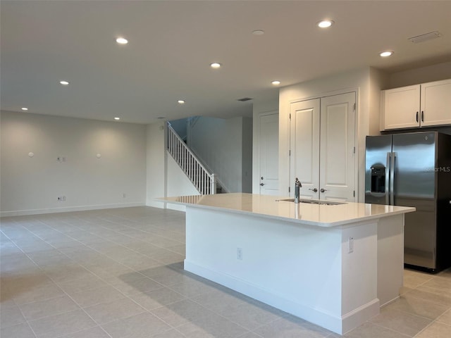 kitchen with white cabinetry, a kitchen island with sink, sink, and stainless steel refrigerator with ice dispenser