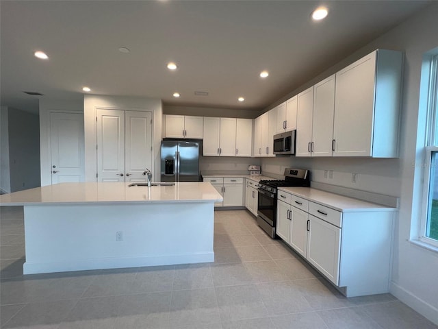 kitchen with a center island with sink, sink, light tile patterned flooring, white cabinetry, and stainless steel appliances