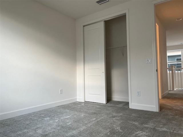 unfurnished bedroom featuring dark colored carpet and a closet