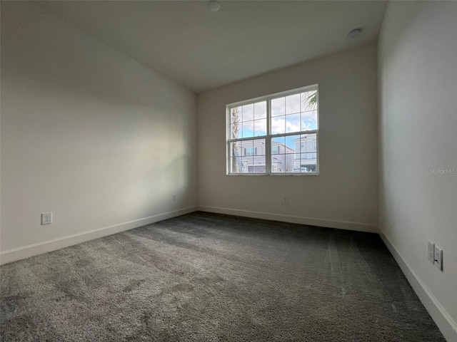 spare room featuring dark carpet and vaulted ceiling