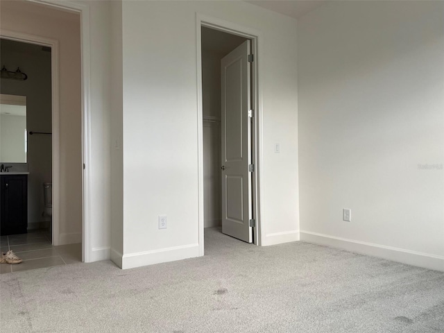 unfurnished bedroom featuring light carpet and ensuite bath