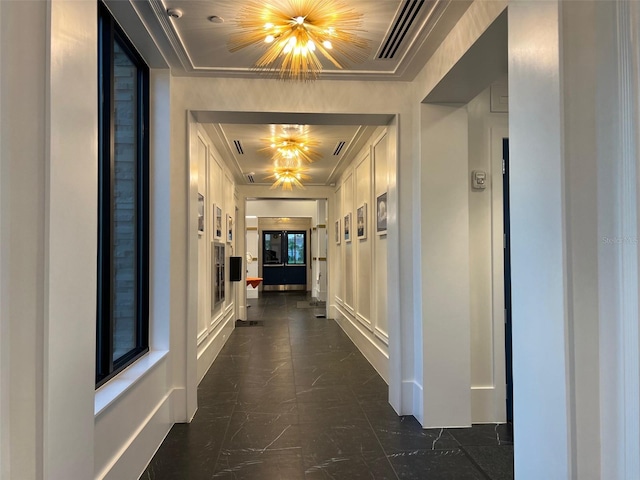 hallway with a chandelier and crown molding